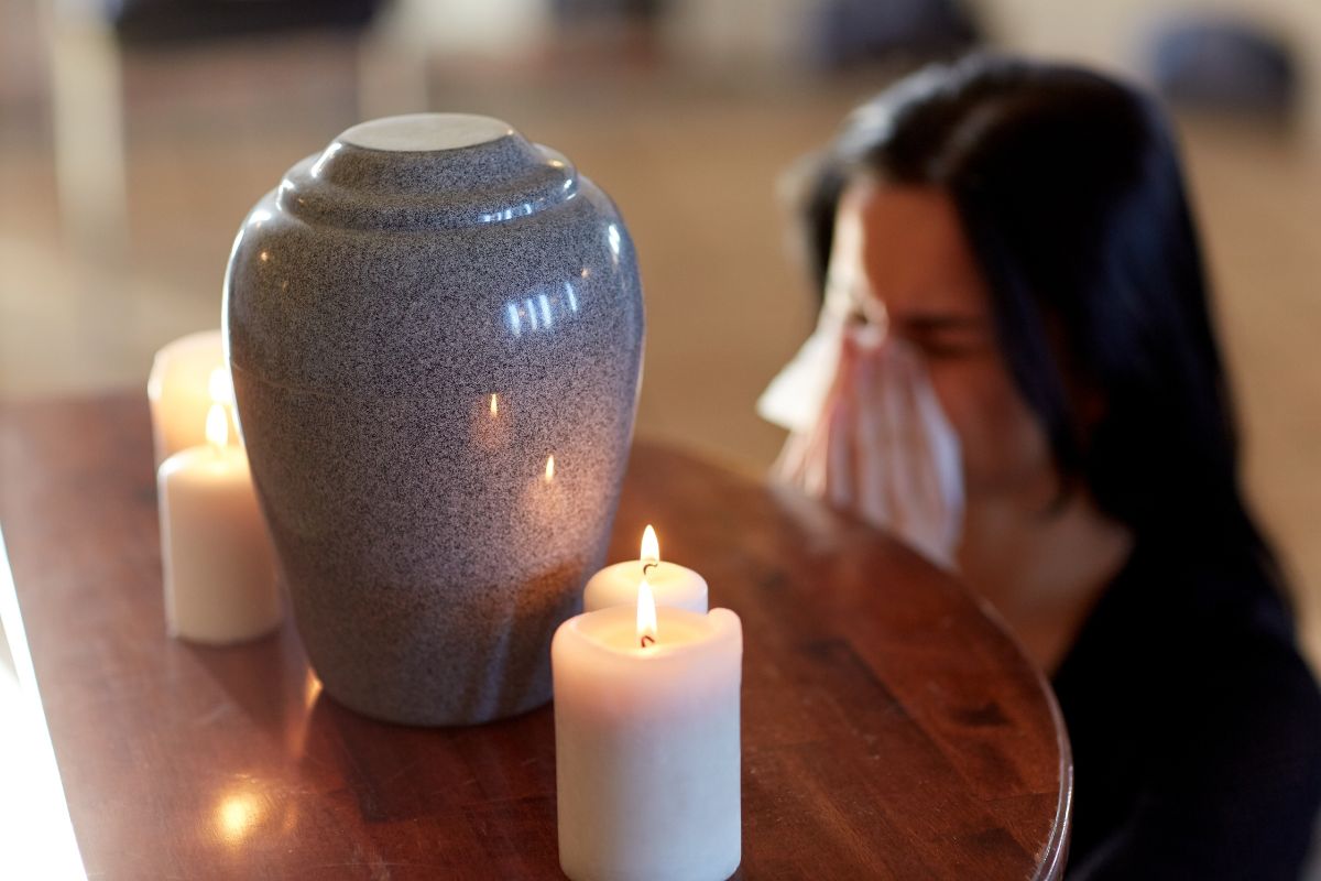 Woman reflecting beside urn and candle